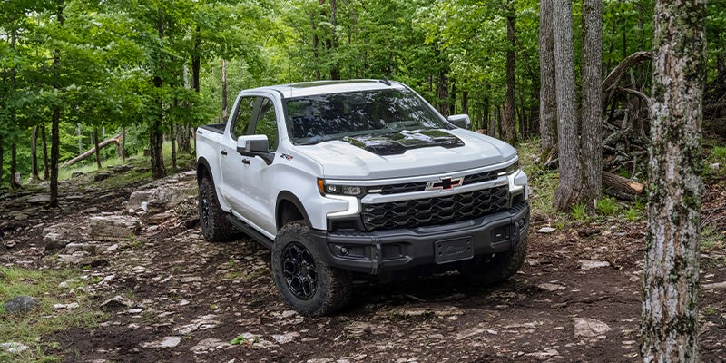 White 2023 Chevrolet Silverado ZR2 driving offroad in forest