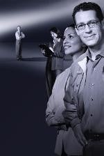 Group of professionally dressed individuals standing in a spotlight, symbolizing teamwork and leadership.