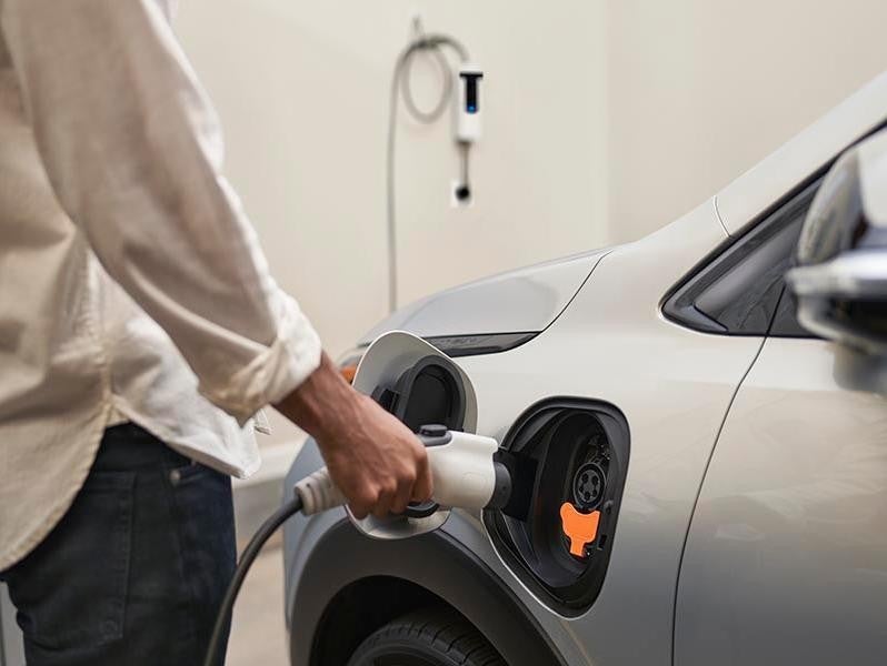 A person pluggn the EV charger to the vehicle at home garage.